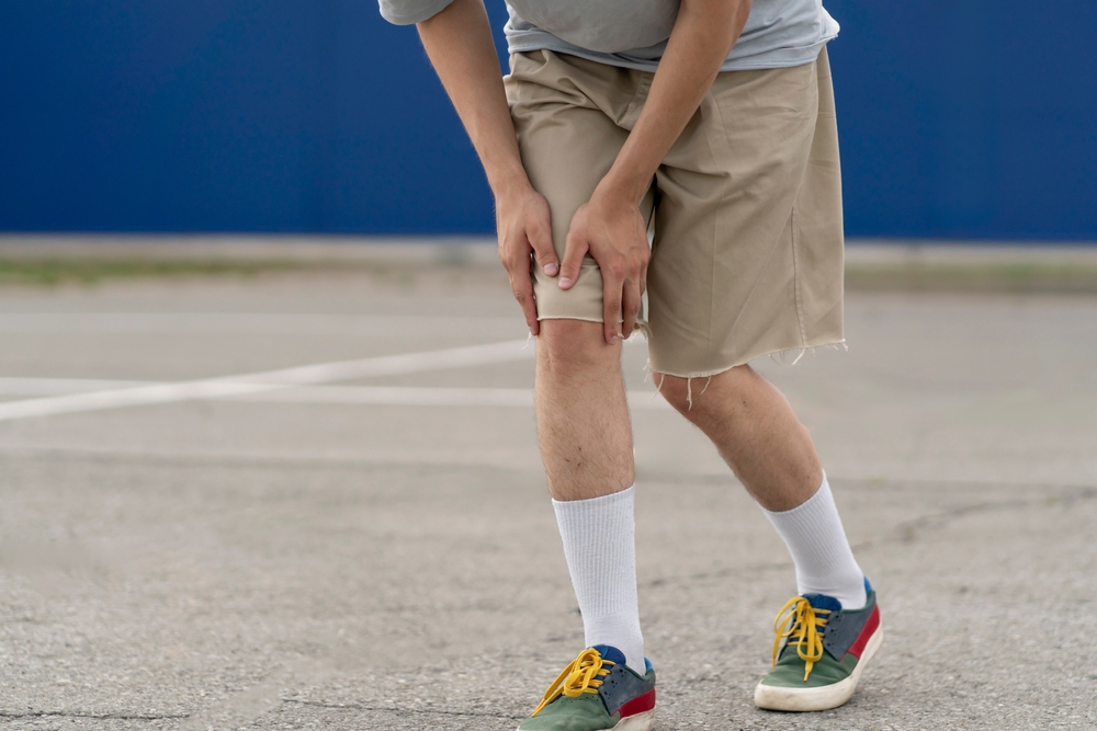 Pedestrian holding knee after being injured in a traffic-related accident
