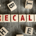 Letter blocks on a wood table spelling out the word RECALL.