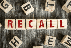 Letter blocks on a wood table spelling out the word RECALL.