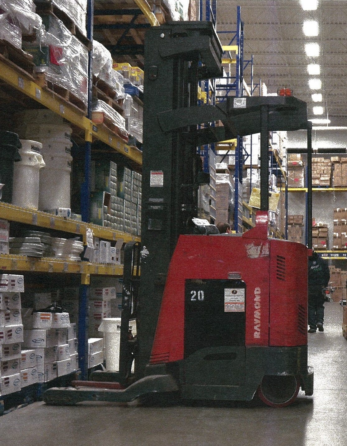 A forklift in a warehouse between two shelves.