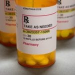 A close-up of several prescription bottles on a gray counter, organized in a triangle.