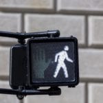 A crosswalk sign with a signal of a person walking.