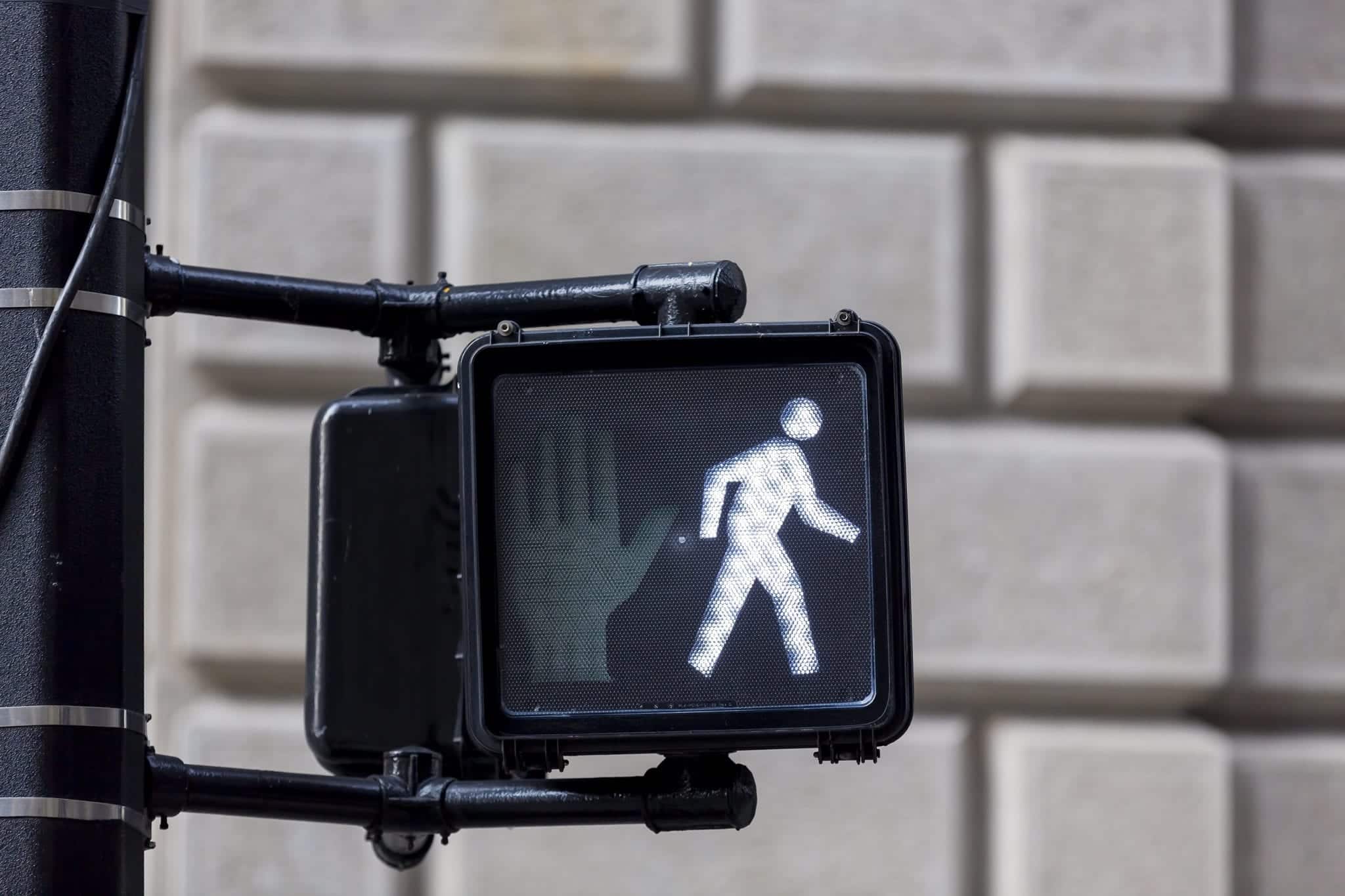 A crosswalk sign with a signal of a person walking.