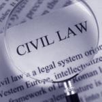 A close-up of an open textbook with a magnifying glass resting on the page and focused on the words CIVIL LAW.