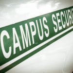 A close-up of the side of a white car with a diagonal green strip with the words CAMPUS SECURITY.