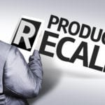 Looking over the shoulder of a man in a business suit at the words Product Recall.