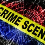 Yellow Crime Scene tape stretched diagonally across the screen with shattered glass in the background colored red white and blue.