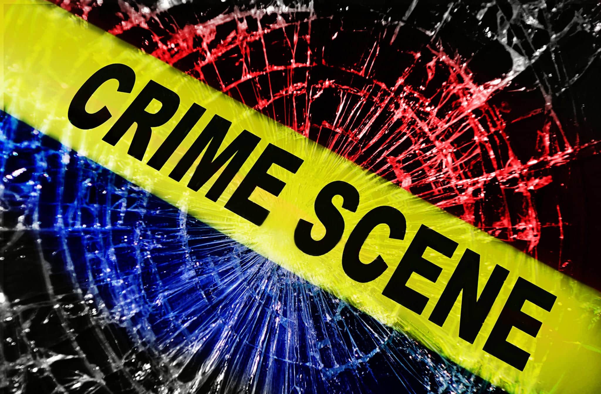 Yellow Crime Scene tape stretched diagonally across the screen with shattered glass in the background colored red white and blue.