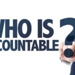 A man in a dark suit in front of a white background holding up his pointer finger with the title, " Who is accountable?"