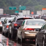 Multiple rows of standstill, bumper to bumper traffic on a shiny wet road.