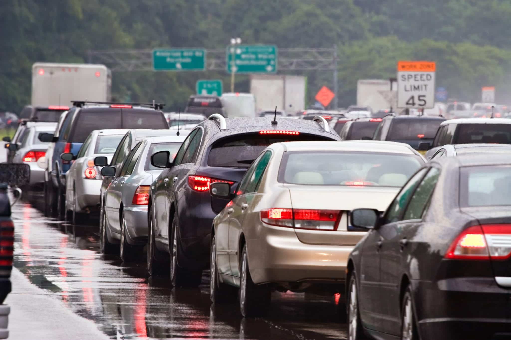 Multiple rows of standstill, bumper to bumper traffic on a shiny wet road.