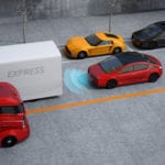 An arial view of a 3D modeled scene of a small red car with a black roof and blue radar beaming from the front of a self-driving car driving behind a tractor trailer on a street lined by parked cars.