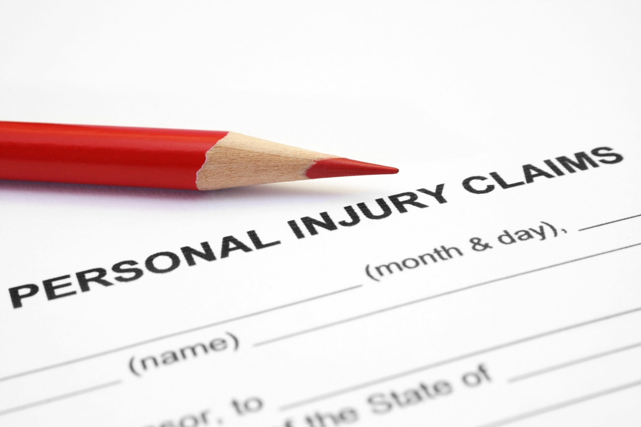 A close-up of a blank form to be filed out with the words Personal Injury Claims at the top and a red colored pencil laid on top of the paper form.