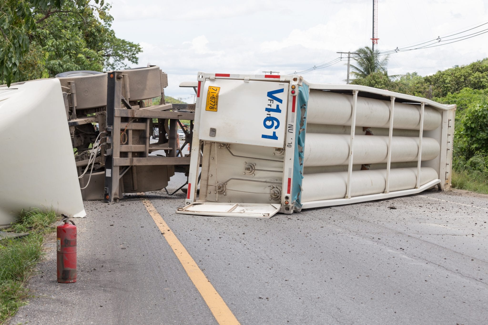 A tractor trailer flipped on its side laying accross the road.