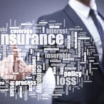 Blurry image of a man in a suit in the background pointing toward a collection of insurance associated words in the foreground.