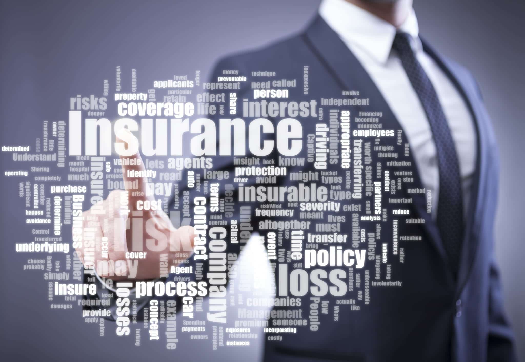 Blurry image of a man in a suit in the background pointing toward a collection of insurance associated words in the foreground.