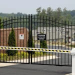 An apartment gate and arm for security measures with apartments in the background.