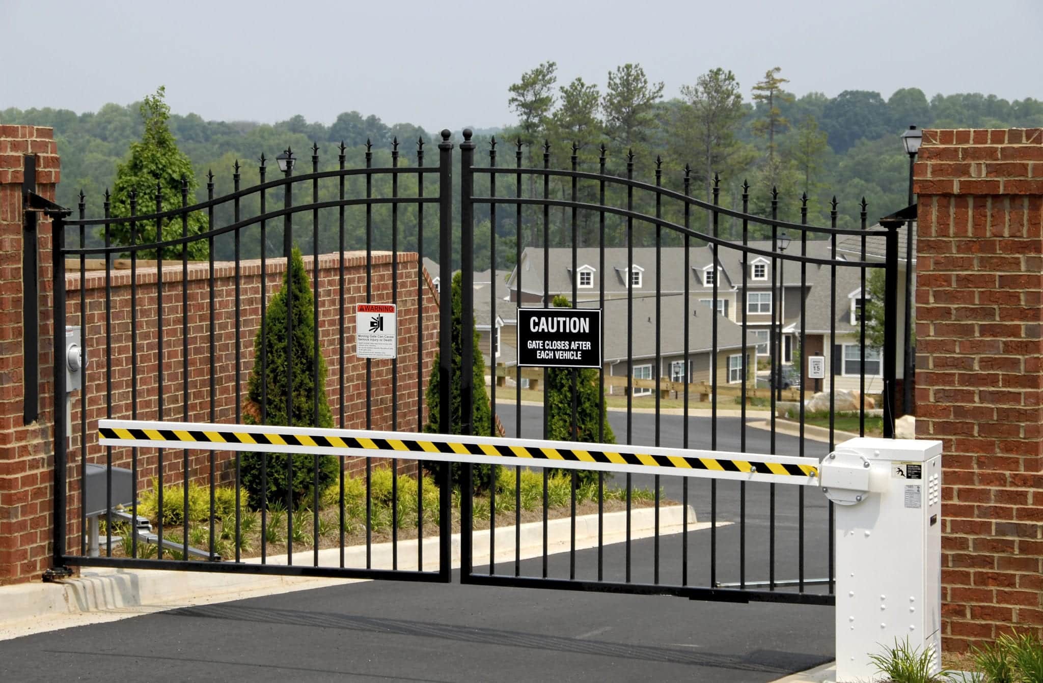 An apartment gate and arm for security measures with apartments in the background.