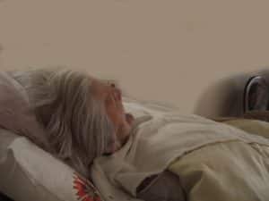 Elderly woman in nursing home bed.