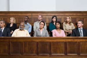 A group of ten women and men, all looking toward their right, sitting in a woodedn jury box.