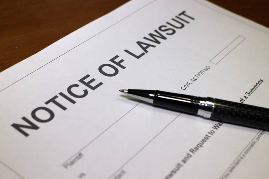 An ink pen lying ona paper that says notice of lawsuit at the top.