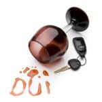 A wine glass on it's side with red wine spilled out in the shape of the letters DUI beside a car key.