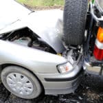 A closeup of a silver car that has rearended a black car.