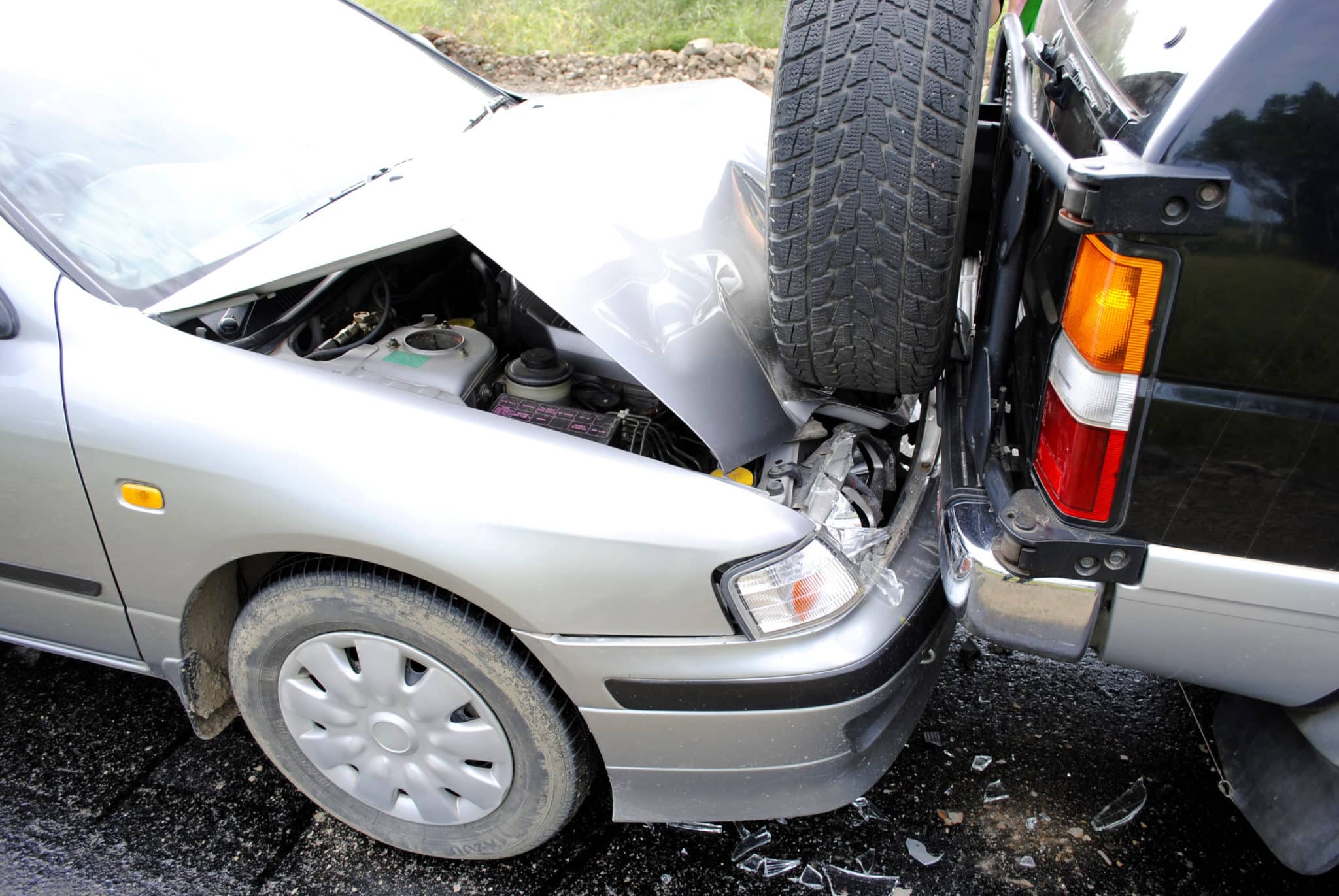 A closeup of a silver car that has rearended a black car.