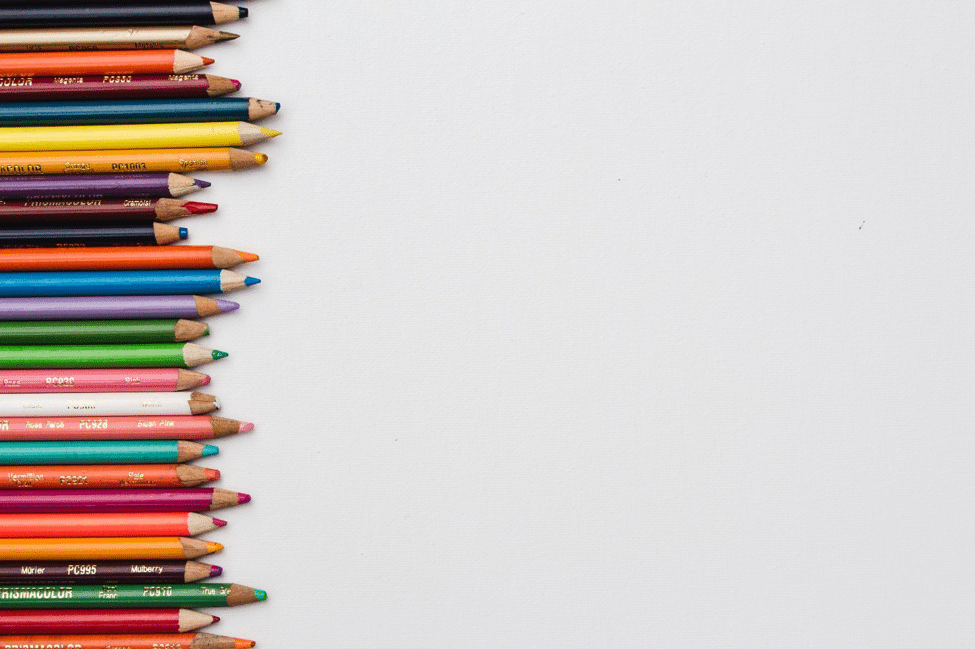 A blank white background with multi-colored pencils of different lengths on the left hand side.