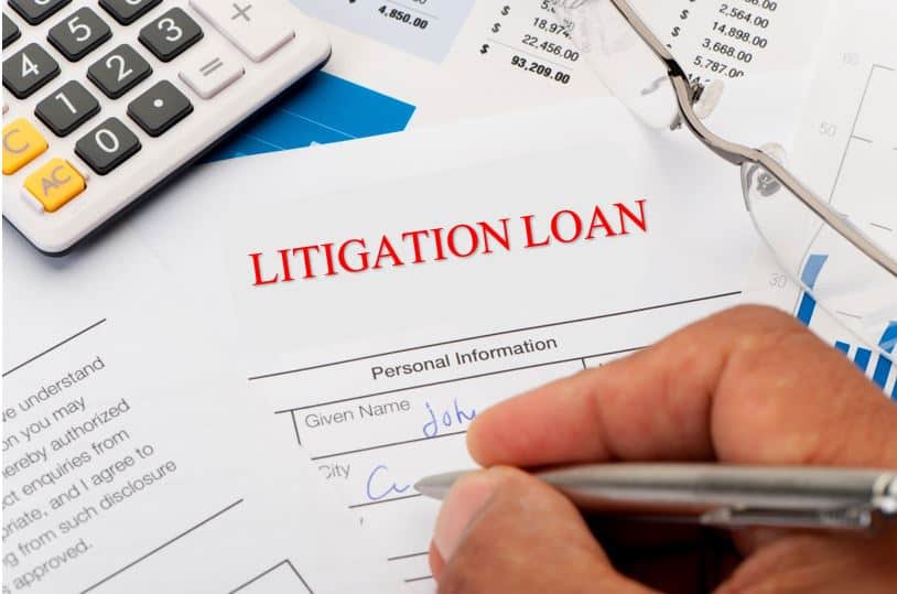 A man's hand holding a pen signing a litigation loan.