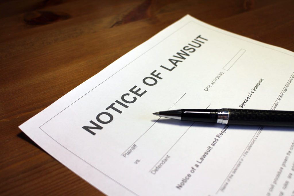 A piece of paper with Notice of Lawsuit printed at the top with a pen laying on the paper.