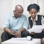 Couple sitting next to each other on a couch discussing documents.