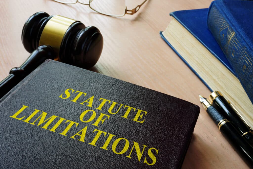 A gavel, eye glasses and a book with the title, Statute of limitations, on a desk.