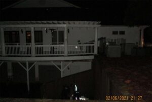 A white building with a deck, without any lights on, in the night.
