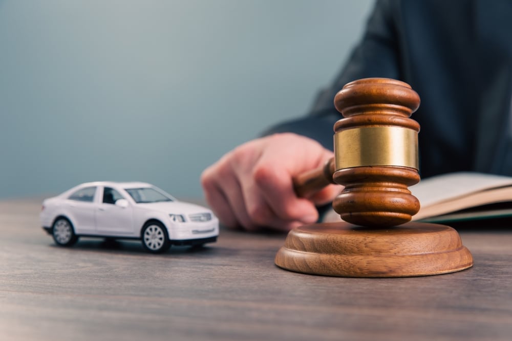 Model car next to a judge’s gavel, representing an accident lawsuit, insurance dispute, or court case related to a vehicle collision.