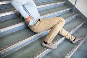 Mature man lying on staircase after slip and fall accident, injury risk and safety hazard