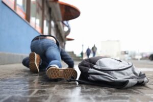 Man with backpack lying on slippery sidewalk after fall