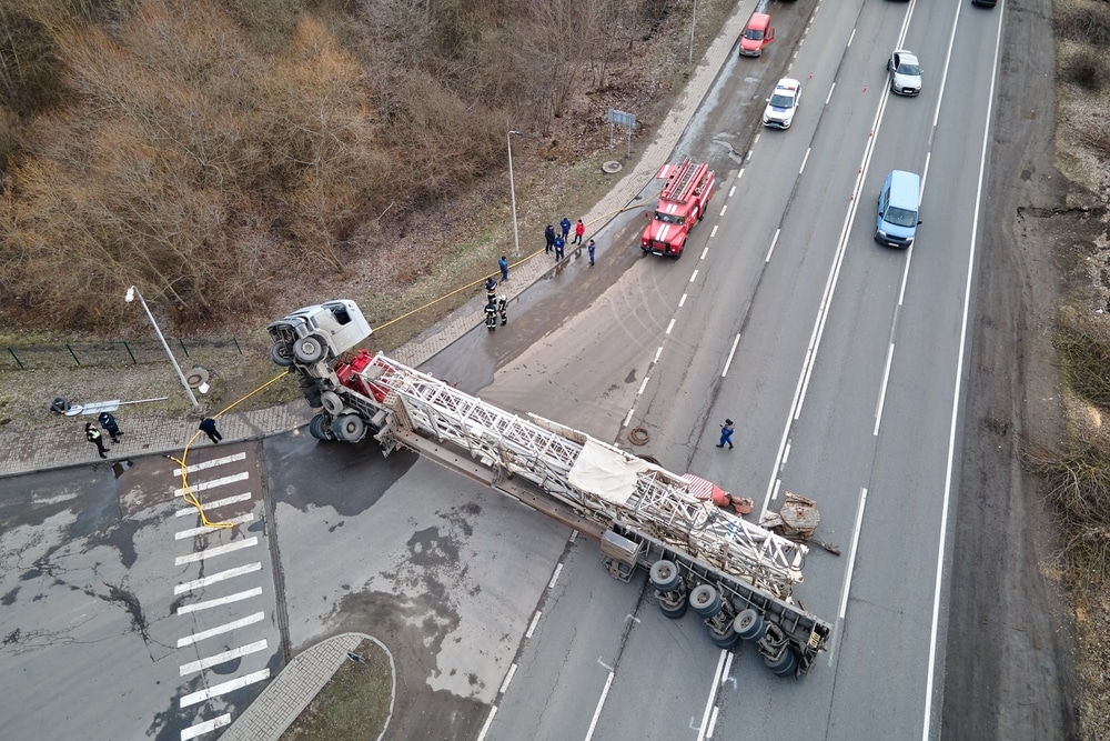 Overturned semi-truck blocking multiple lanes on a highway with emergency crews on scene after a serious crash.