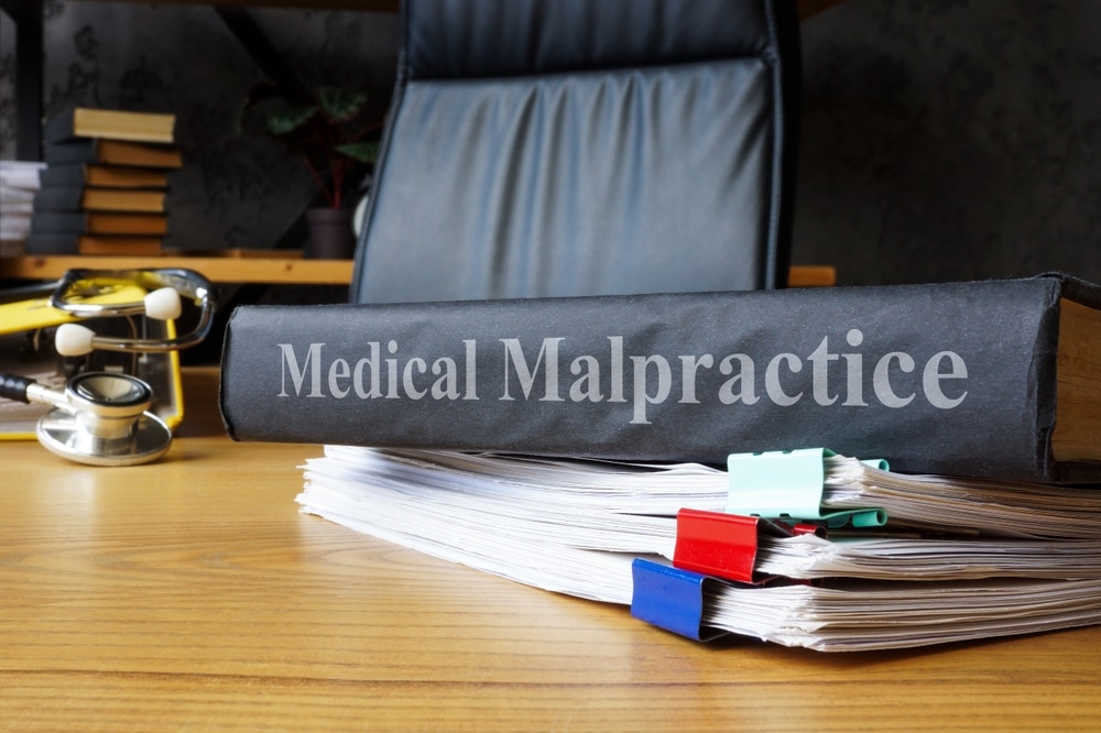 Medical malpractice case file on a desk with legal documents, a stethoscope, and office supplies