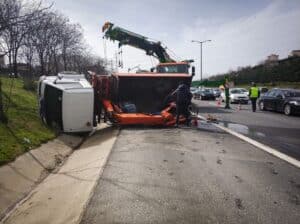 Rollover truck accident with tow crews working at the scene on a busy highway.